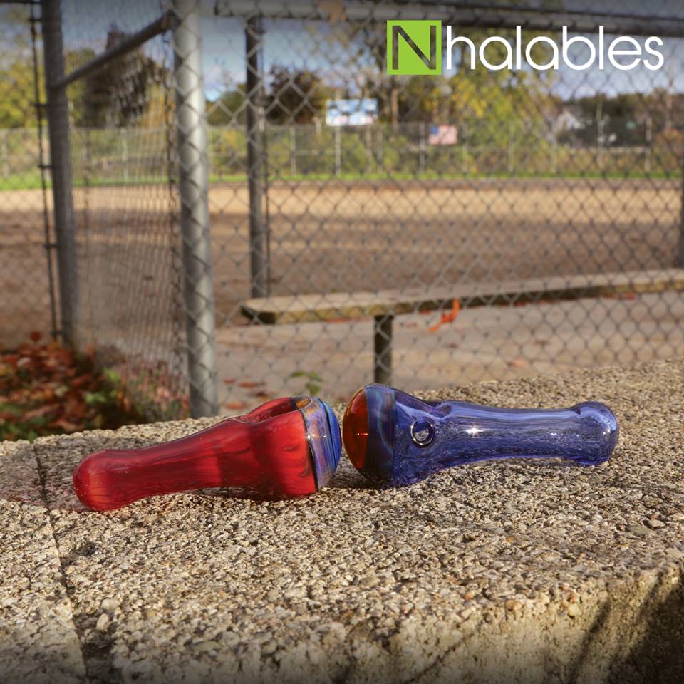 Nhalables Social Post showing two Eyehole Glass Hand Pipes sitting on a rock in front of a baseball field.