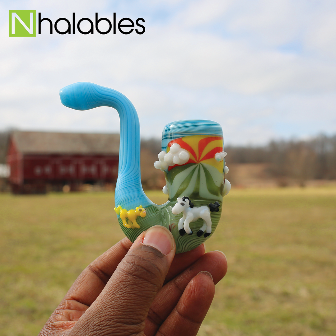 Nhalables Social Post showing a JEM Glass (Jamie Erin Morse) sculpted animal sherlock being held in a hand in a field in front of a red barn. 