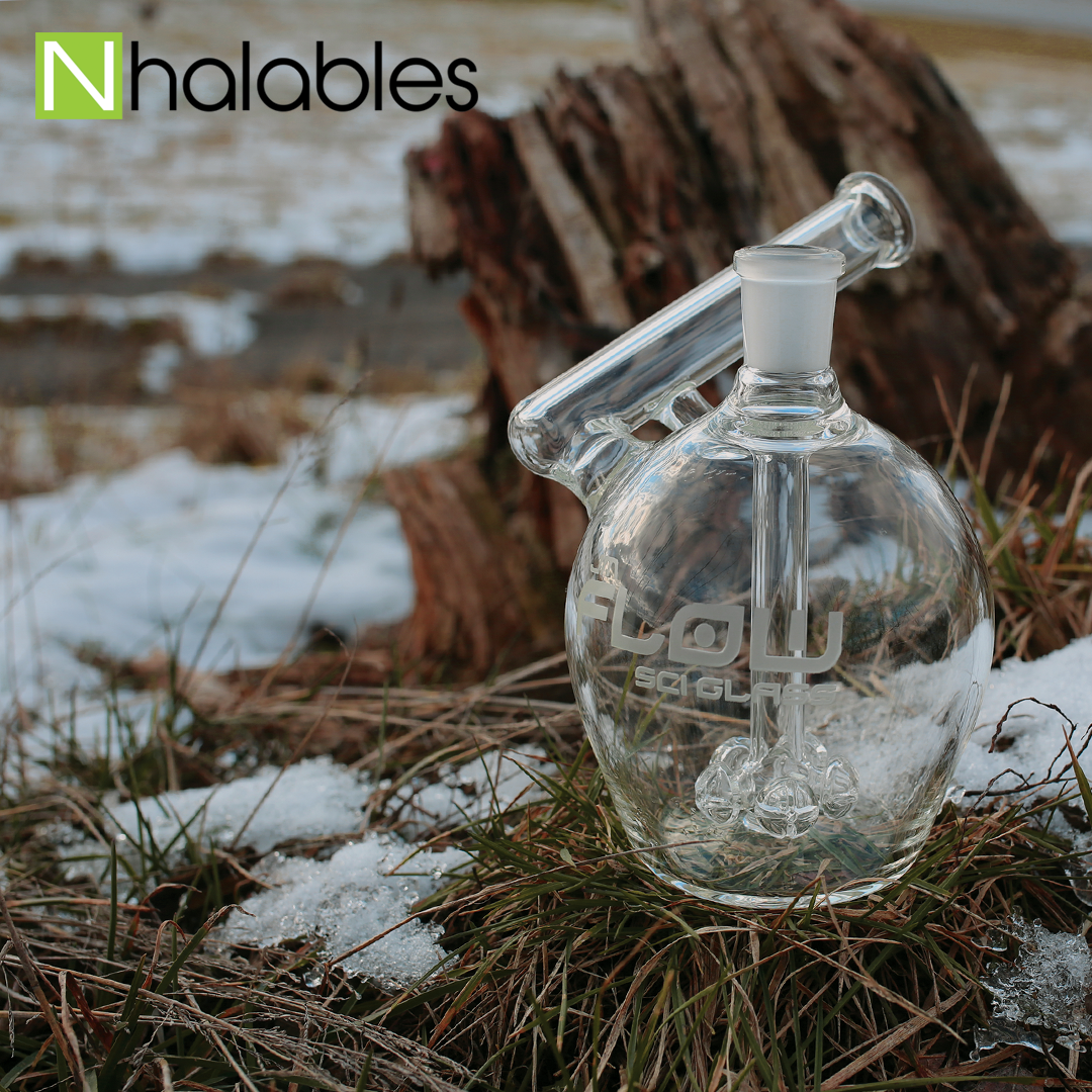 Nhalables Social Post Showing a Jm Flow Apple Rig with a cross percolator sitting on grass in front of a stump.