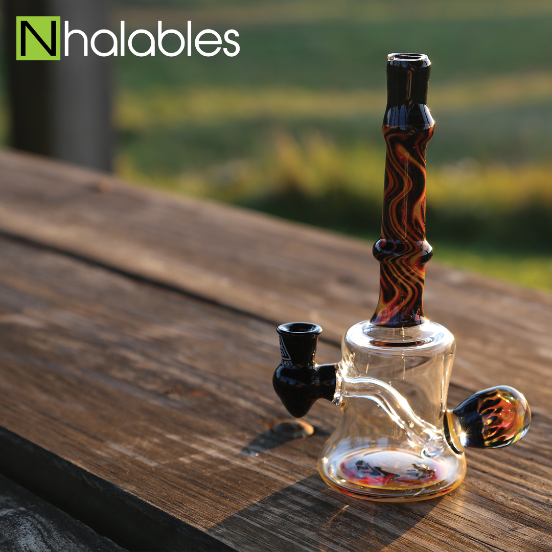 Nhalables Social Post showing a Cleveland Based Artists Rival Glass Oil Rig sitting on a picnic bench at sunset