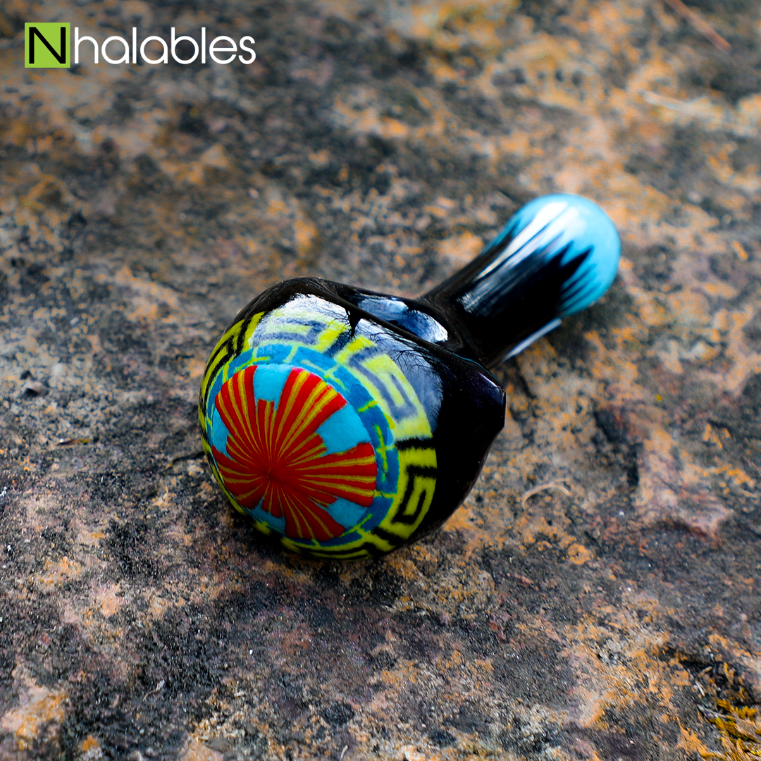 Nhalables Social Image for a Aztec Hand pipe by Michigan Based Glassblower Hoffman Glass sitting on a rock.