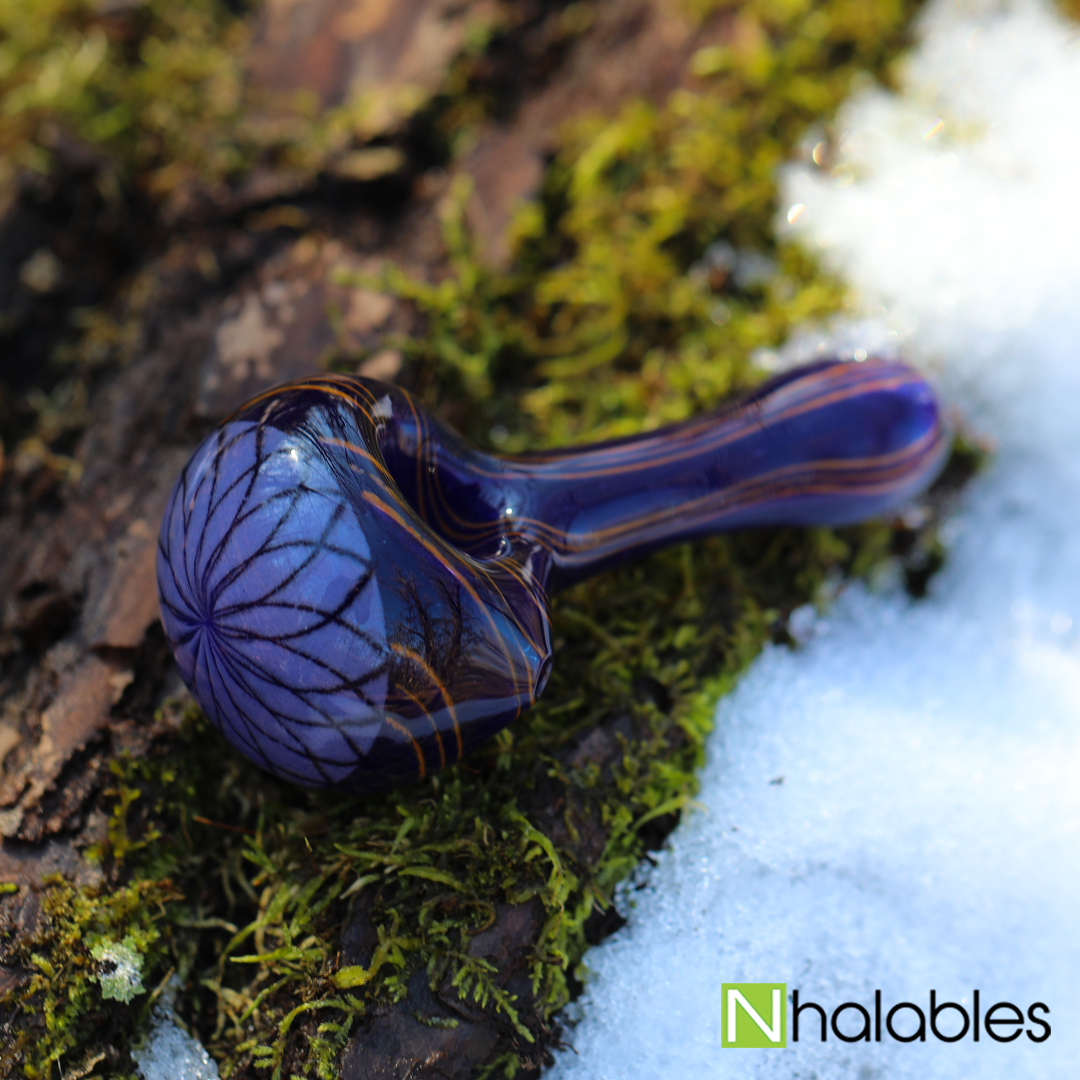 Nhalables Social Image showing a Reticello Hand Pipe by Steven Hoffman Glass sitting on a log with some snow and moss by it. 