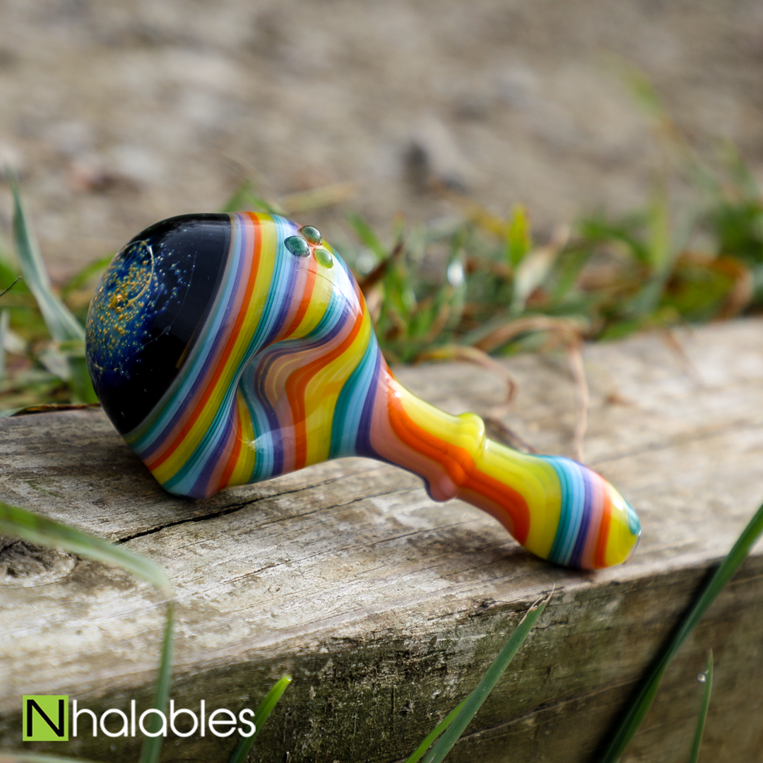 Nhalables Cosmic Capped Hand Pipe By Ozarks based artist JEM Glass (Jamie Erin Morse) sitting on a piece of wood with grass in the background