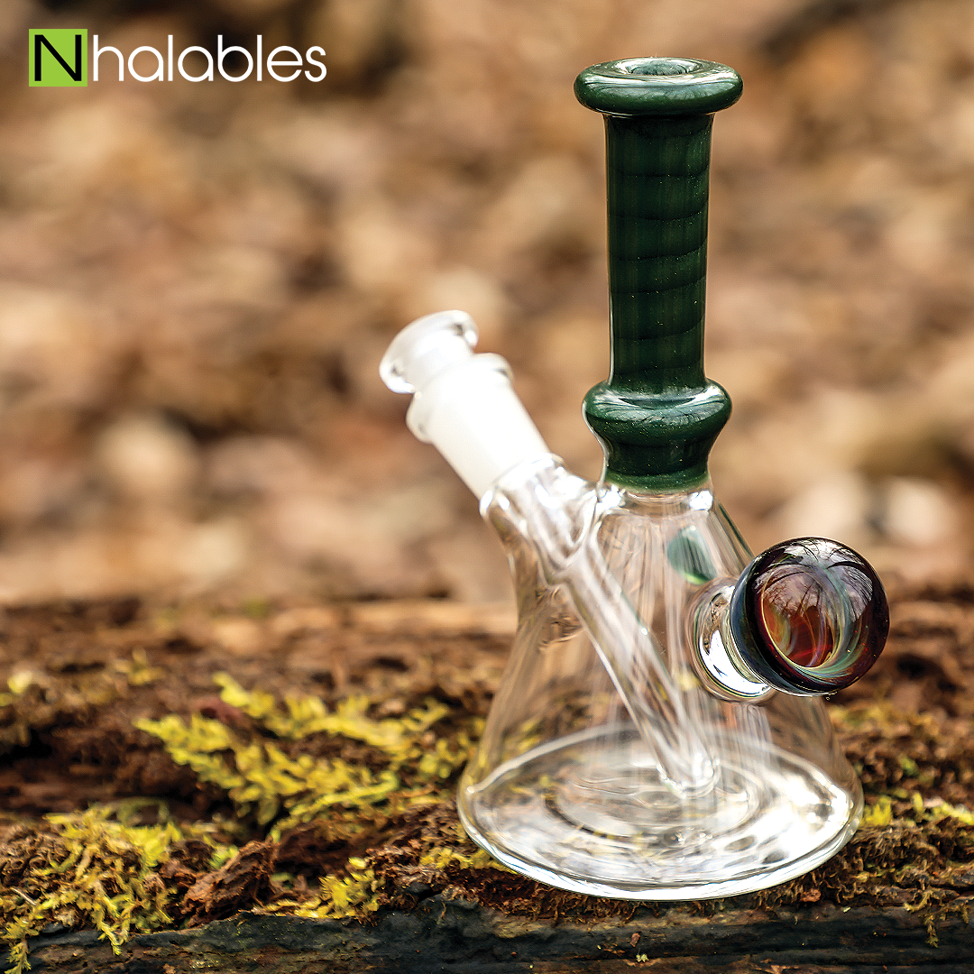 Nhalables Social Post showing a "Tuskum Glass" Green Sparkle Flask sitting on a mossy log.